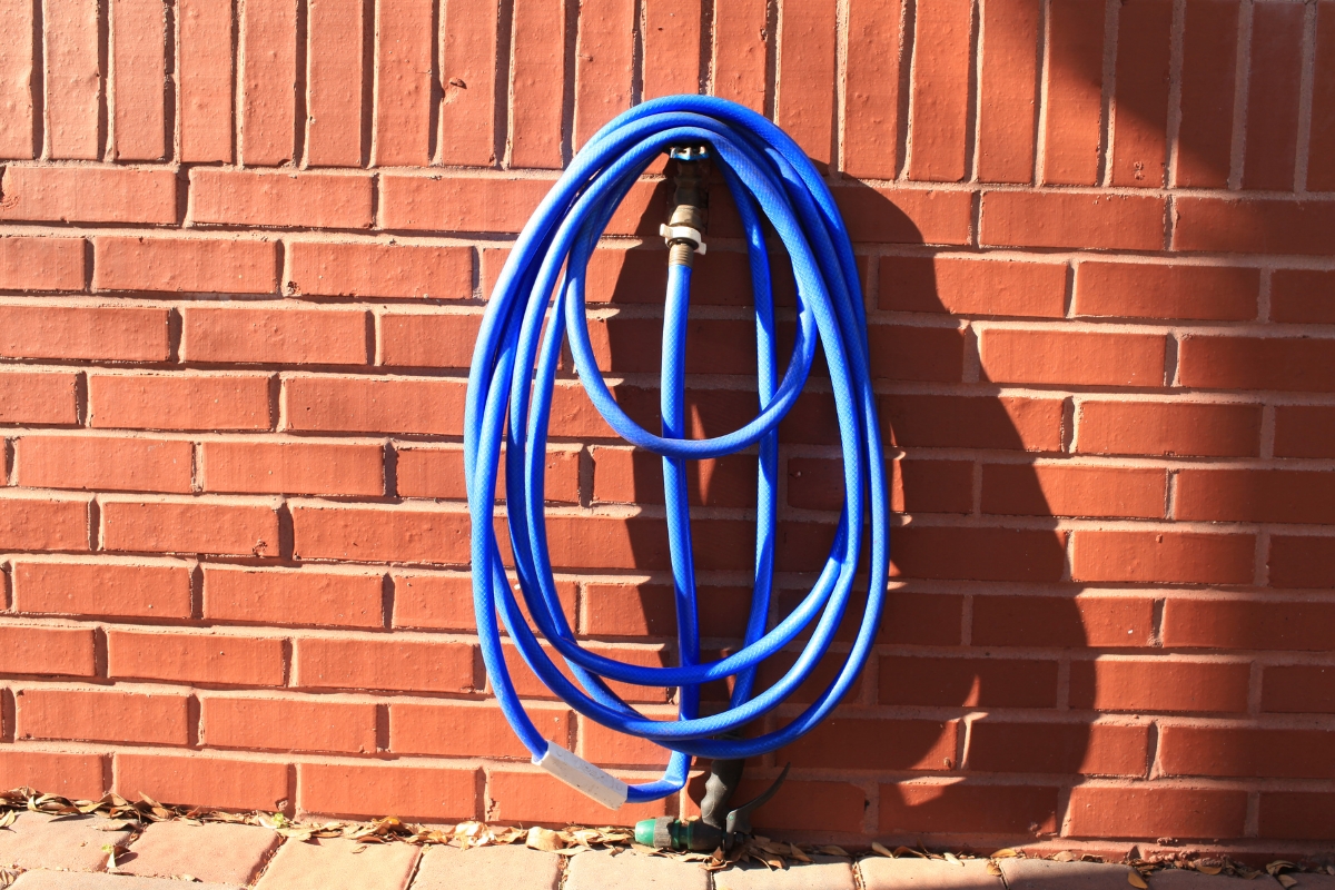 Rolled up outdoor hose on a brick wall