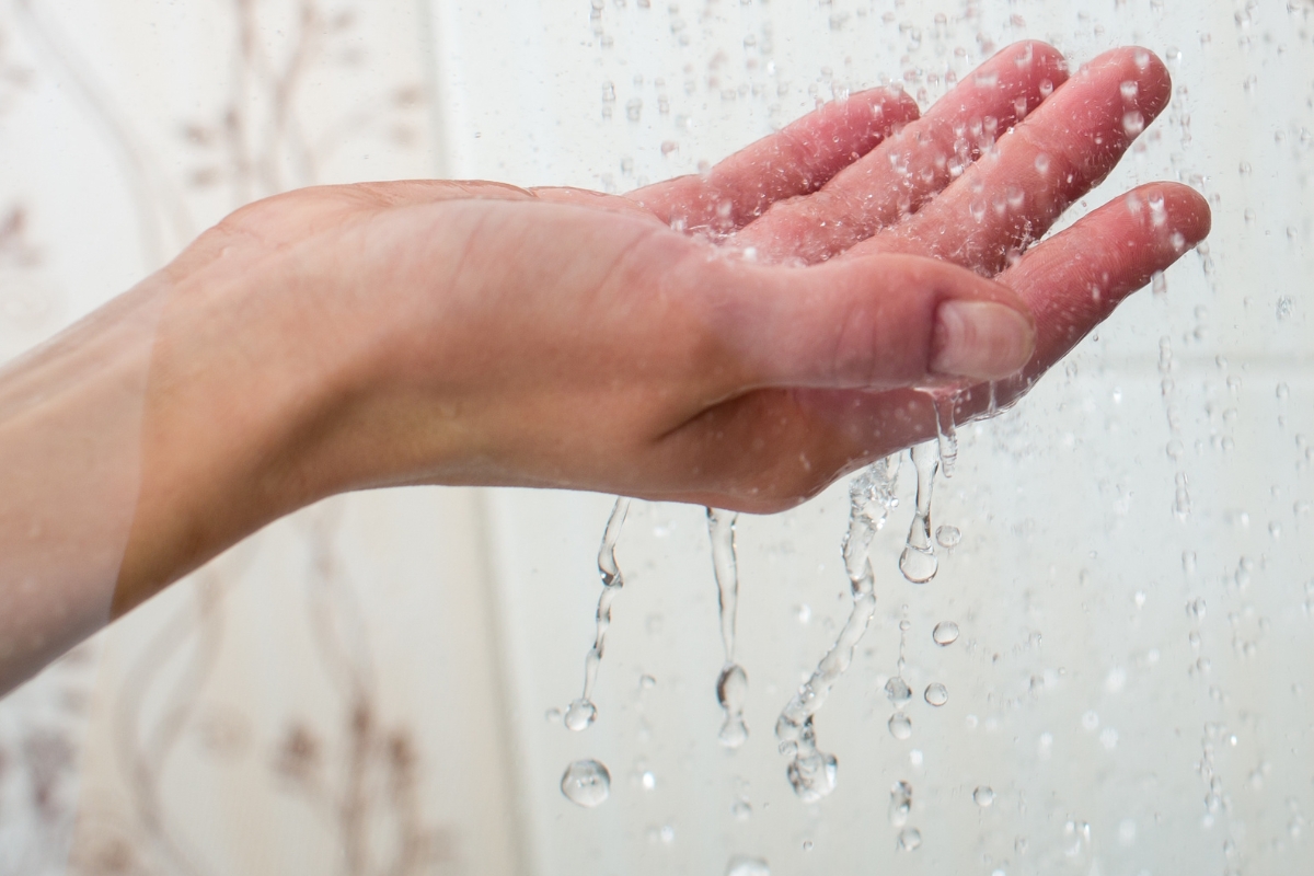 hand catching water falling from faucet with water pressure problem