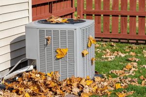 Outdoor AC unit covered in orange leaves in fall