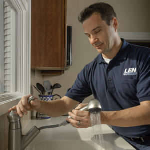 Len The Plumber technician testing pull-out spray head on a kitchen faucet in the DC area.